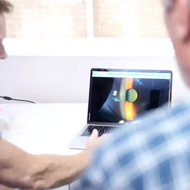 Clinicians viewing and discussing a slit lamp image on a laptop screen