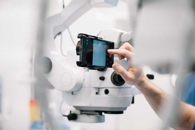 a man changing the focus of a optical system to record his surgery